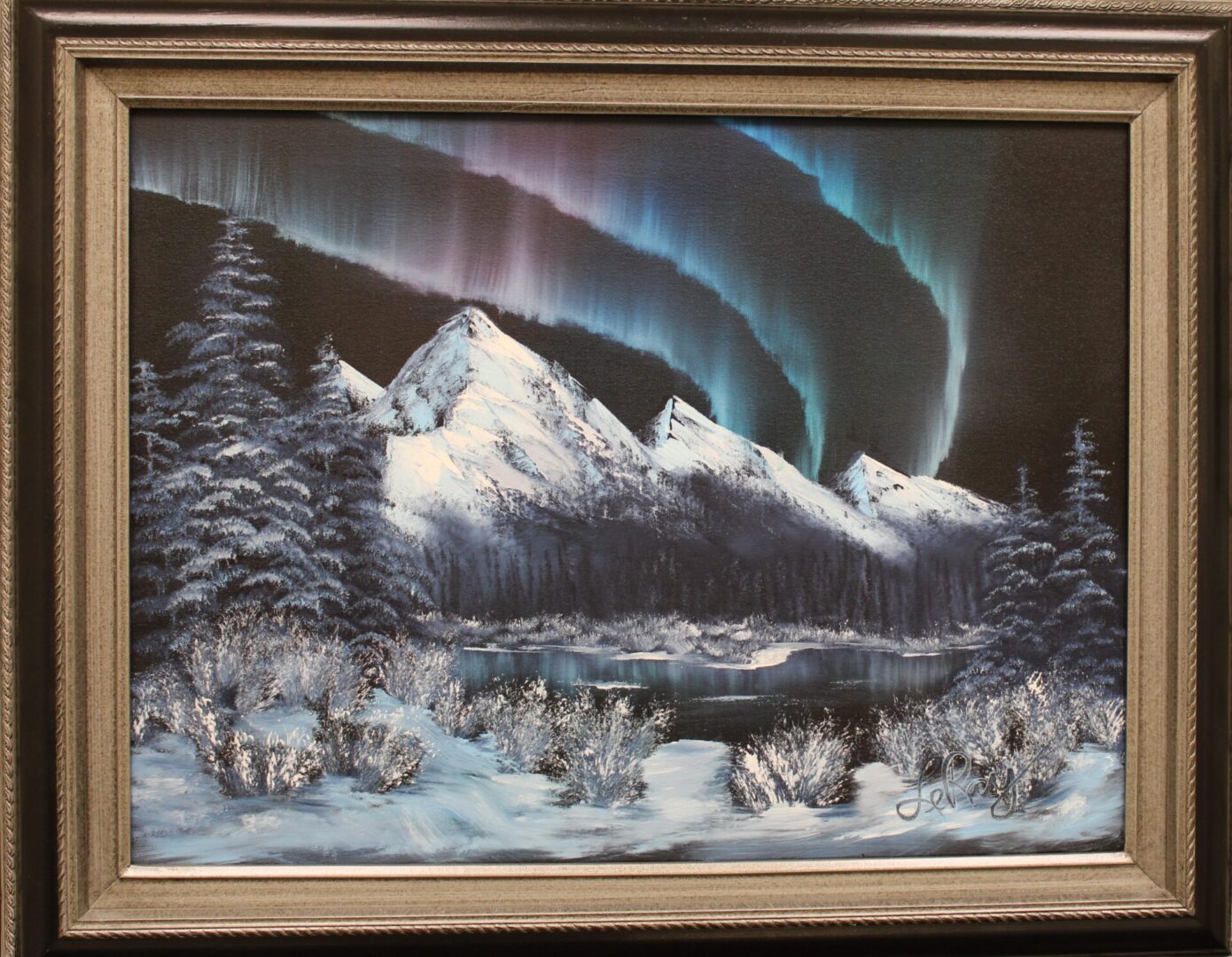 framed painting of northern lights with mountain and snowy trees
