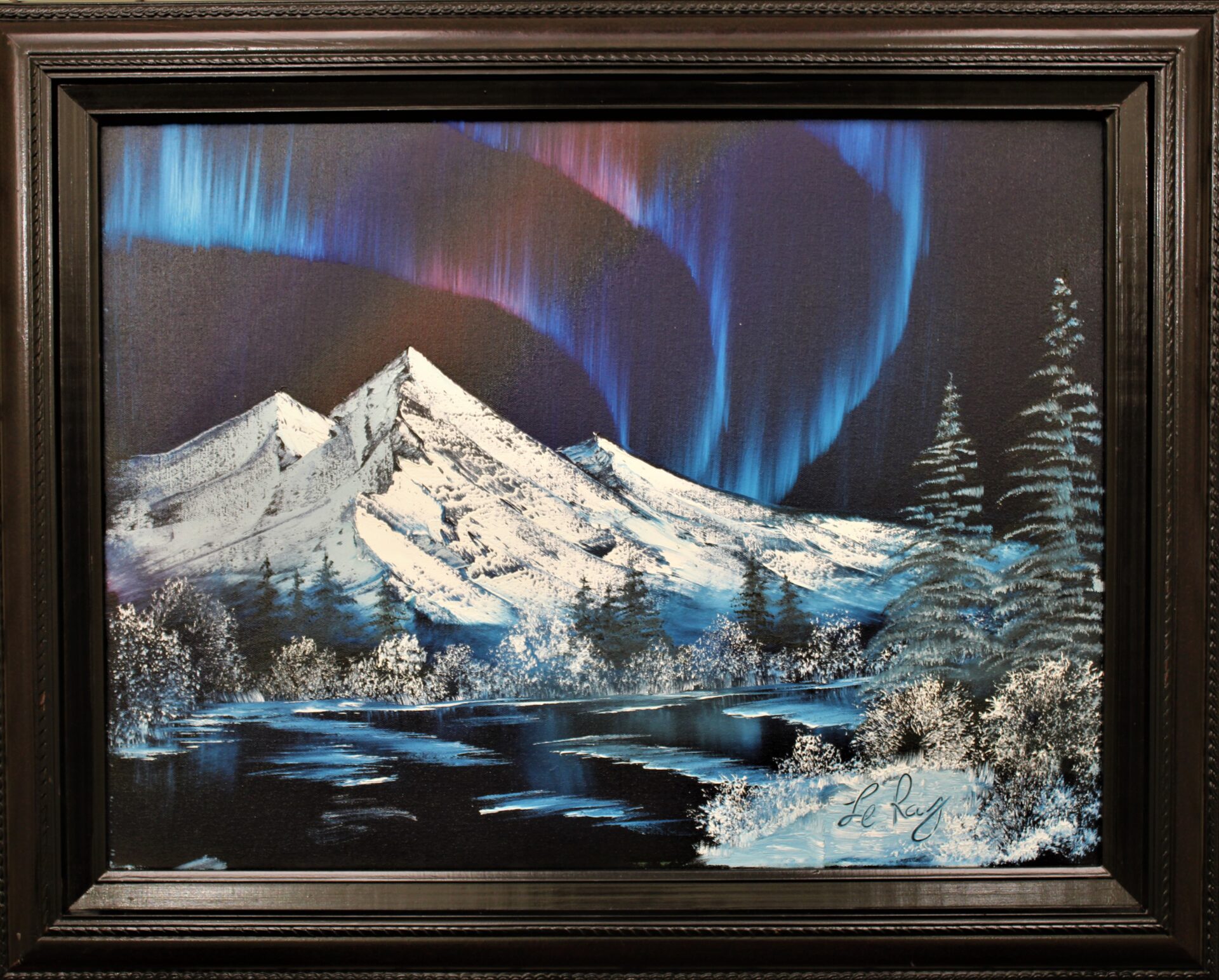 framed painting of northern lights with mountain and trees