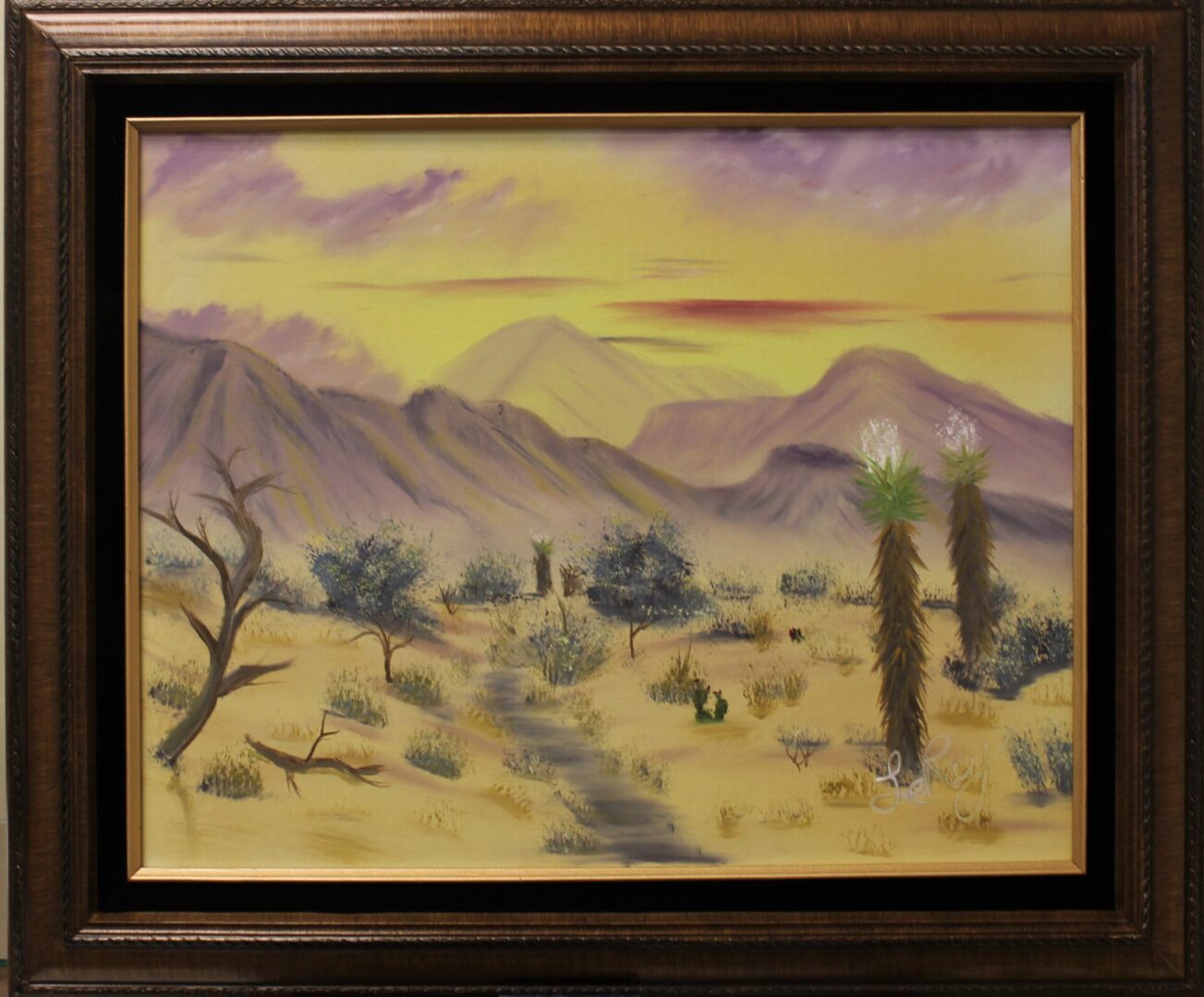 A painting of Desert Sunrise in a brown frame.